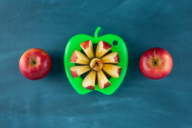 Fresh sliced red apples placed on blue surface.