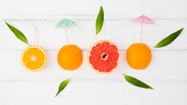 Fresh slices of citruses with decorative umbrellas and green leaves