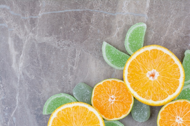 Fresh slices of orange with sweet marmalades on marble background.