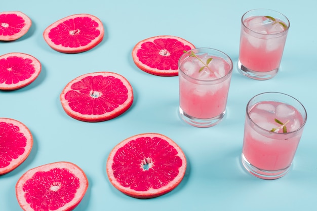 Fresh slices of ripe grapefruit and cold juice on blue background