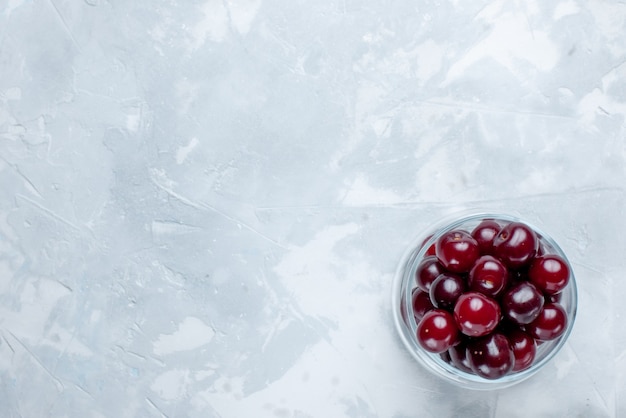 fresh sour cherries inside little glass cup on light-white