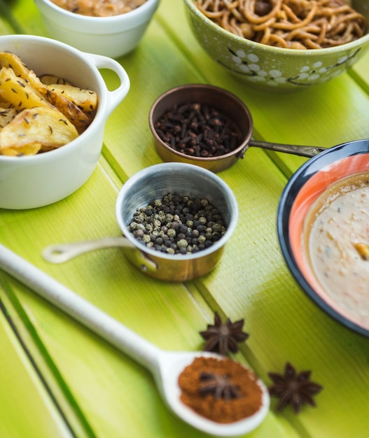 Fresh spices near dishes on green table