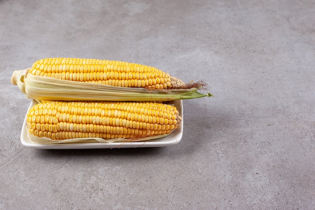 Fresh sweet ears of corn isolated on white plate