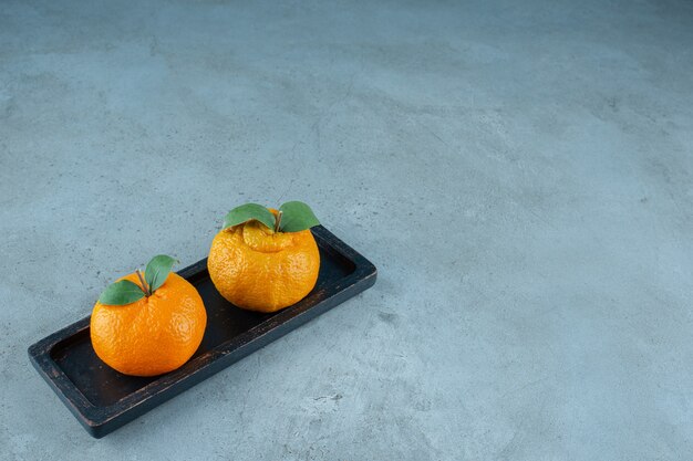 Fresh tangerines on a wooden plate , on the marble background. High quality photo