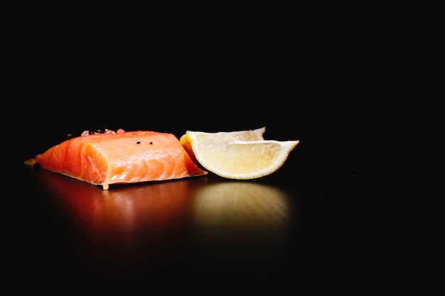 Free photo fresh, tasty and healthy food. red salmon and lemon on black background isolated