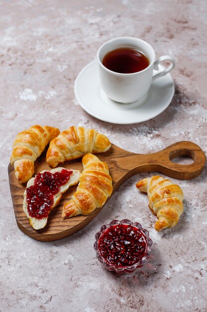 Fresh tasty homemade croissants with raspberry jam on grey-white . French pastry