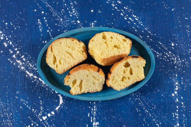 Fresh tasty sliced cakes placed on blue plate.