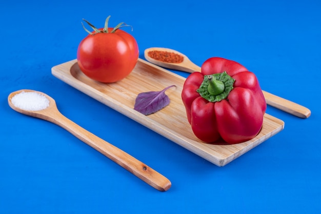 Free Photo fresh tomato and red bell pepper on wooden plate with spices