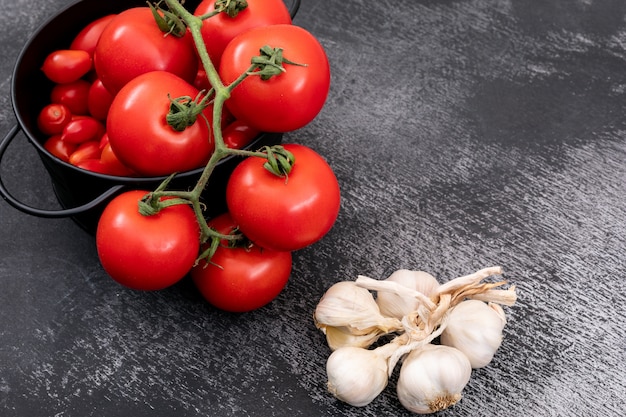 Fresh tomatoes in a pot and garlics