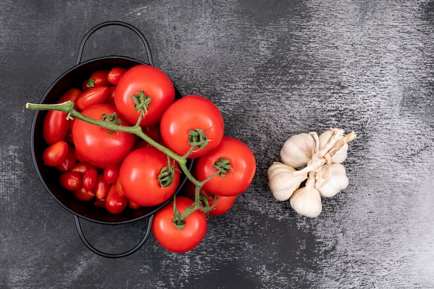 Fresh tomatoes in a pot and garlics