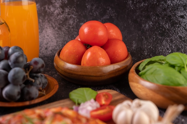 Fresh tomatoes in a wooden cup, grapes and orange juice in a glass.