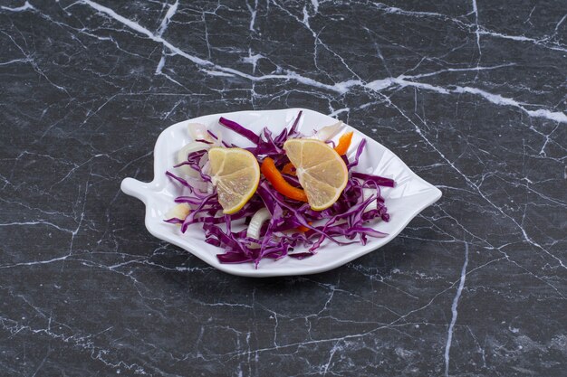 Free photo fresh vegetable salad on white plate over black.