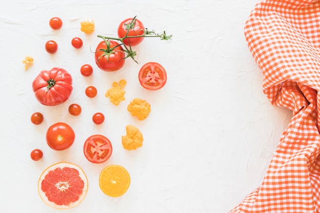 Fresh vegetables and checkered pattern napkin on white backdrop