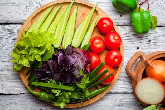 Fresh vegetables cucumber, tomato, onion, pepper on wooden cutting board