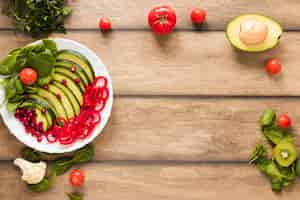 Free photo fresh vegetables and fruits salad in white plate on wooden table