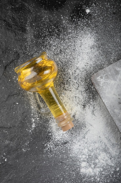 Free photo fresh wheat floor spilled on wooden board with glass of oil