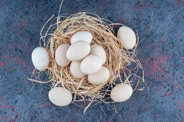 Free photo fresh white and brown chicken eggs with hay .