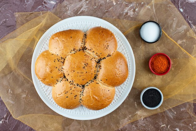 Fresh white buns with salt and pepper on a light background . 