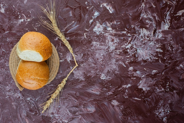 Free photo fresh white buns with wheat ears on a light background .