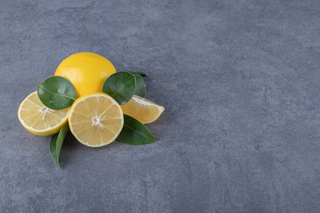 Fresh whole or half cut lemons on grey background.