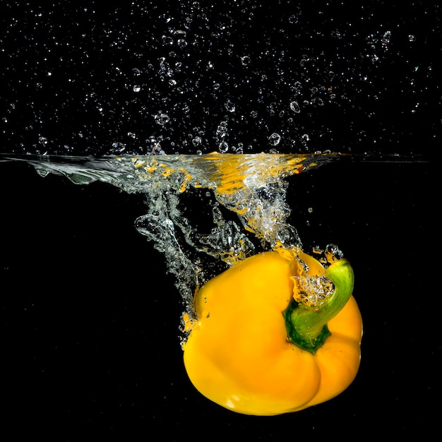 Free Photo fresh yellow bell pepper falling into the water with a splash and air bubble