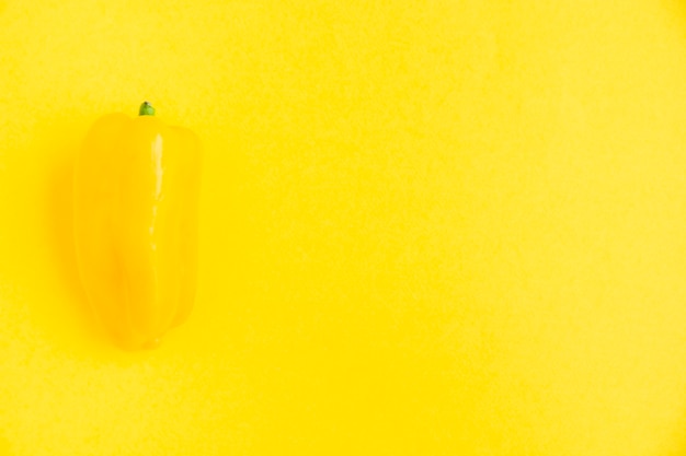 Fresh yellow bell pepper on yellow surface