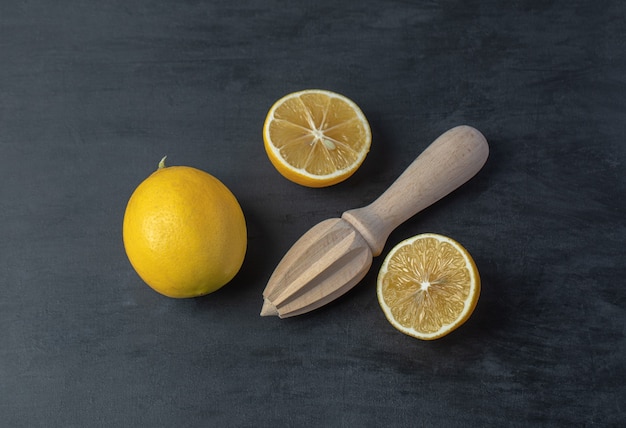 Fresh yellow sliced and whole lemons with a wooden reamer .