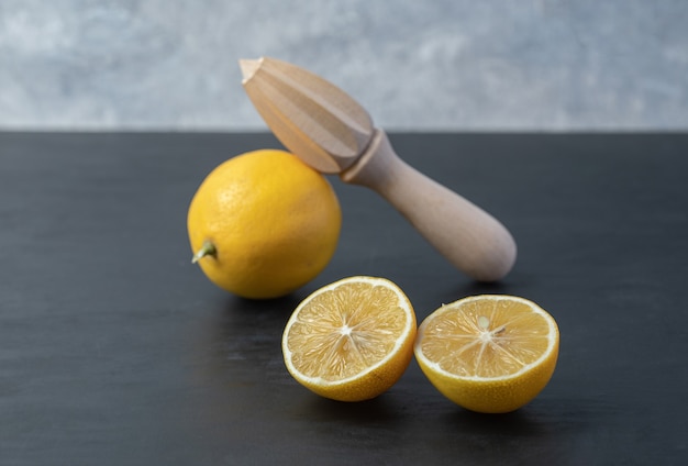 Fresh yellow sliced and whole lemons with a wooden reamer .