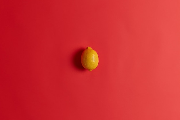 Free photo fresh yellow sour lemon rich in vitamin c, folate, fiber and potassium to strengthen your immunity, cure cold or flu. succulent juicy tropical citrus fruit isolated isolated on red background.