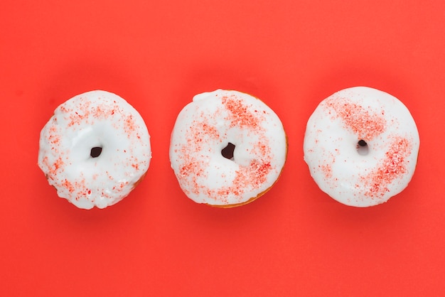 Free photo fresh yummy white chocolate donuts on red background