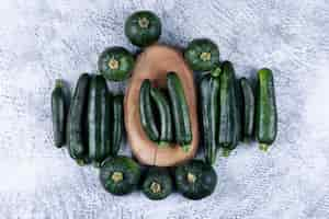 Free photo fresh zucchinis on a stub and around flat lay on a gray textured table