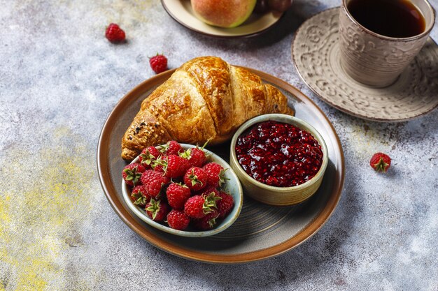 Freshly baked croissants with raspberry jam and raspberry fruits.