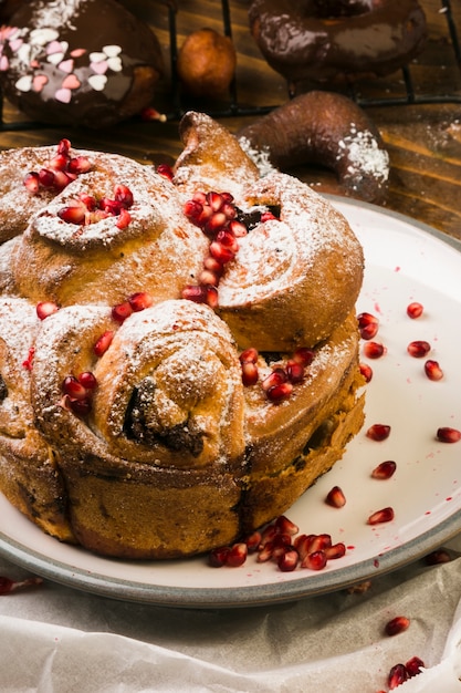 Free photo freshly baked sweet food garnished with pomegranate seed and powder sugar on white plate