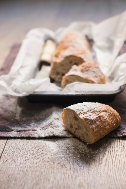 Freshly halved baked bread dusted with flour on wooden table