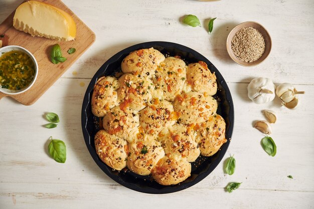 Freshly-made delicious cheese bubble pizza bread with ingredients and cheese on a white table