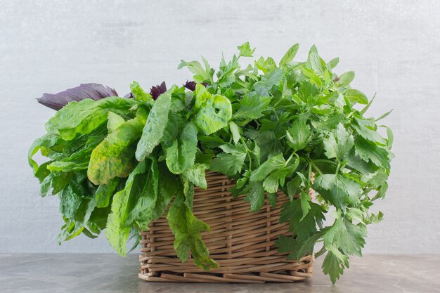 Freshly picked and washed basket of greens on marble.