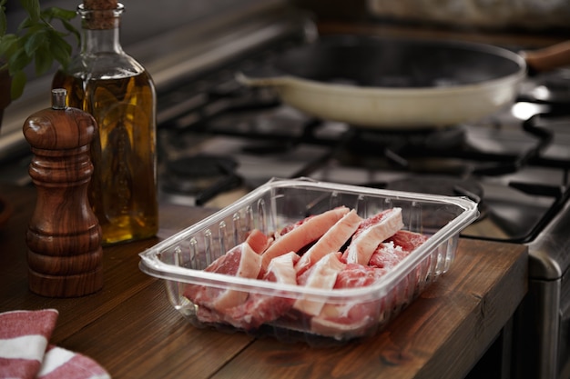 Freshly sliced steak next to a range with grilling pan and oil, pepper and basil