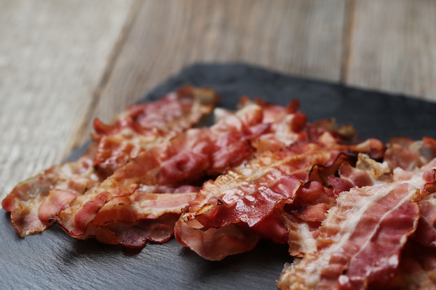 Fried bacon on black stone plate