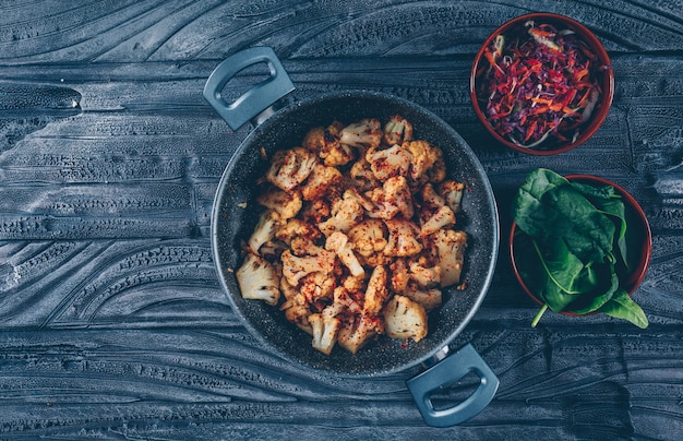 Free Photo fried cauliflower in a pot with vegetable salad, green top view on a dark wooden background. space for text