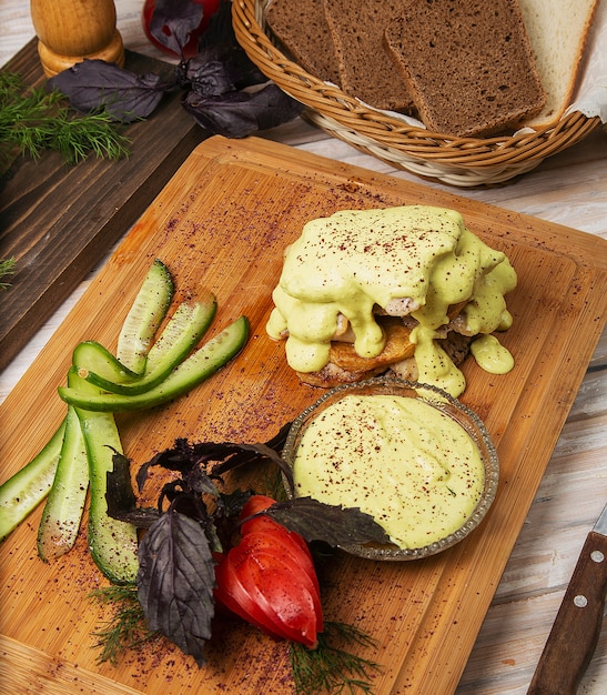 Fried chicken, fish fillet with melted cheese and tomato, cucumber salad on a wooden board