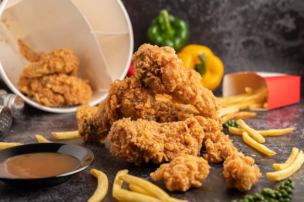 Fried Chicken and French Fries on Black Cement Floor.