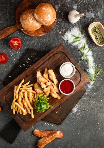 Fried chicken and french fries on a wooden board