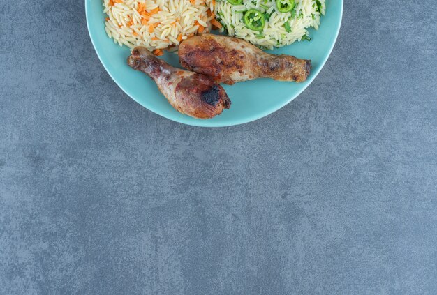 Fried chicken legs and rice on blue plate. 