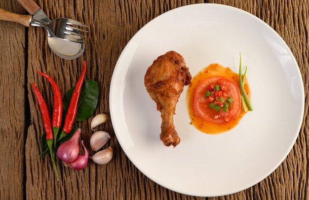 Free Photo fried chicken legs on a white plate with sauce and garlic, shallot, chili.