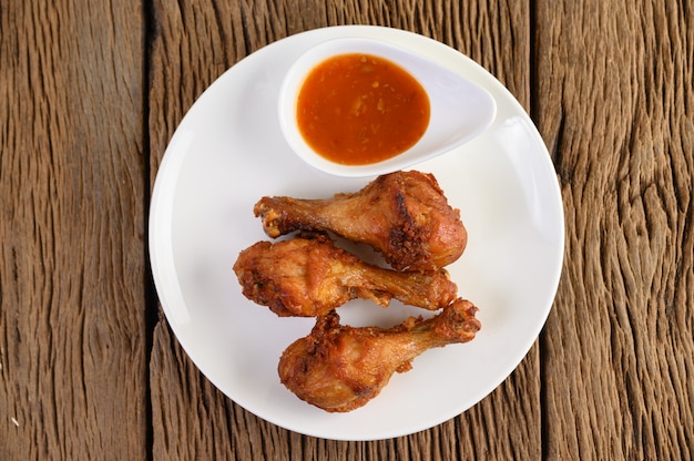 Fried chicken legs on a white plate with sauce.