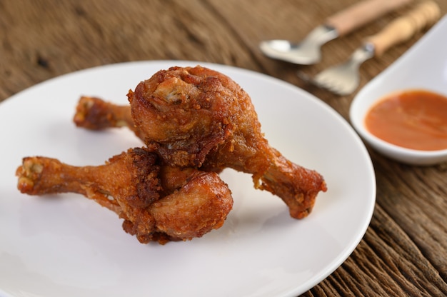 Free photo fried chicken legs on a white plate with spoon, fork, and sauce.