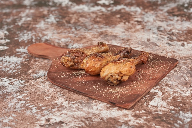 Fried chicken legs on wooden board.