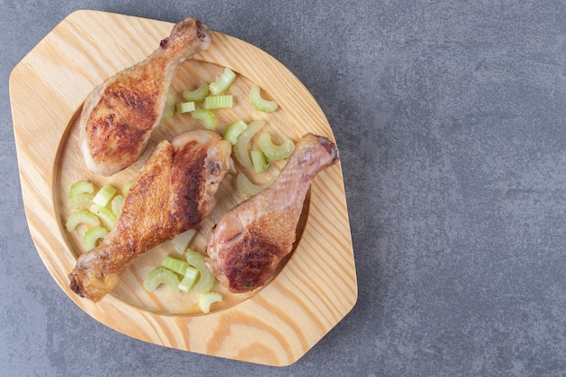 Fried chicken legs on wooden plate.