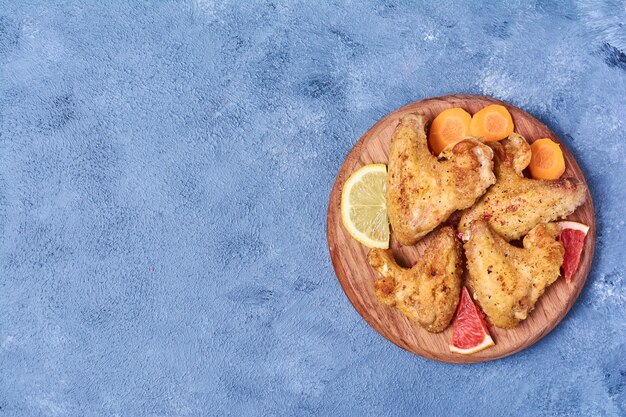 Fried chicken wings on a wooden board on blue