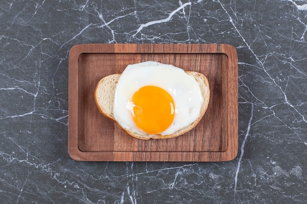 Free photo fried egg on bread sliced on the board , on the marble surface